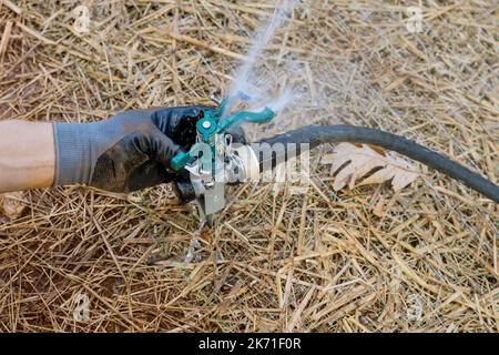 Giardinaggio architettura paesaggistica da parte di un tecnico professionista che installa un irrigatore per prato che innaffia il prato vicino a una nuova casa Foto Stock