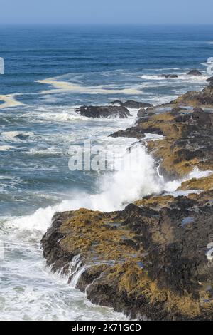 Le onde si schiantano a riva dall'Oceano Pacifico sulla costa dell'Oregon con un oceano blu e un cielo e rocce colorate Foto Stock
