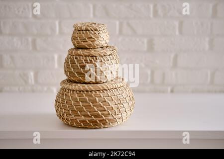 Primo piano della scatola a tre flussi rotondi con coperchio sul tavolo bianco. Cofanetti in vimini da riporre su sfondo bianco. Articoli per la casa Foto Stock