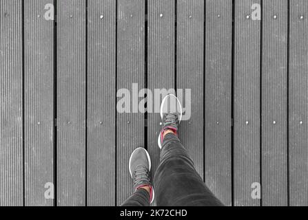 Gambe in sneaker su piattaforma in legno. Foto Stock