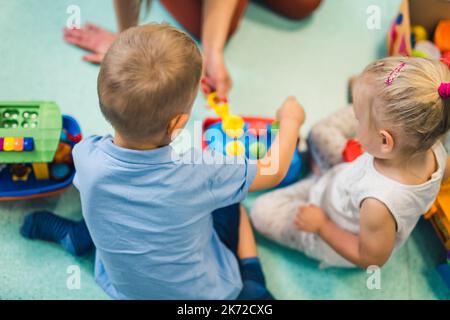 bambini piccoli che giocano con i giocattoli nel nido, concetto di asilo interno. Foto di alta qualità Foto Stock