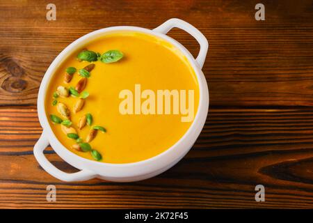 Zuppa cremosa di zucca in un recipiente con semi e basilico Foto Stock