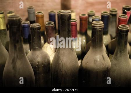 Antica cantina sotterranea con vecchie bottiglie di vino aperte polverose Foto Stock