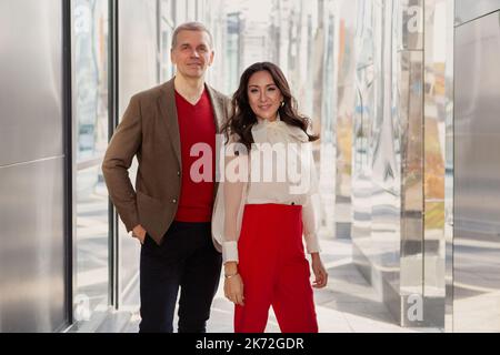 Abbigliamento alla moda, business casual. Uomo d'affari rispettabile che indossa giacca e maglione marrone e Donna in pantaloni rossi e un look elegante camicia bianca Foto Stock