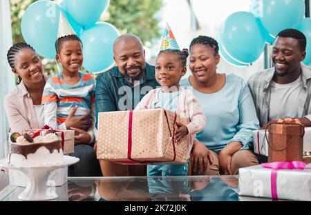 Mi chiedo che cosa sia in questo. una bambina che apre i regali alla sua festa di compleanno. Foto Stock