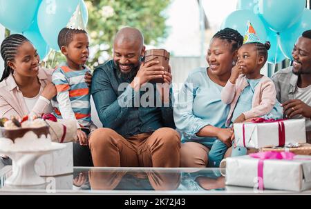 Mi chiedo che cosa c'è qui... un uomo che scuote una scatola che ha ricevuto alla sua festa di compleanno. Foto Stock