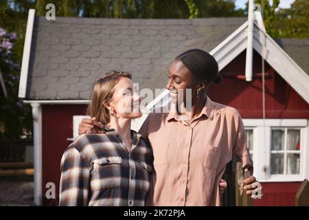 Donne sorridenti in piedi di fronte a casa Foto Stock