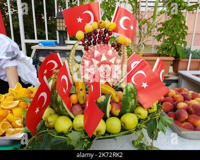 Frutta fresca estiva in un cesto di cocomero decorato con bandiere turche. Composizione con frutta assortita Foto Stock