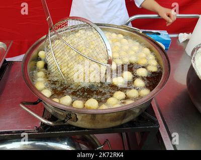 Cuocere le palle di cagliata in olio bollente. Ciambelle turche Lokma Foto Stock