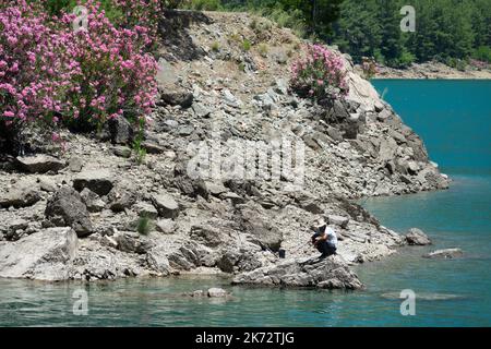 Manavgat, Turchia - 05 giugno 2019: Un pescatore cattura i pesci su un lago tra le scogliere di montagna nel Canyon Verde Foto Stock