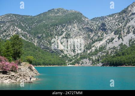 Manavgat, Turchia - 05 giugno 2019: Un pescatore cattura i pesci su un lago tra le scogliere di montagna nel Canyon Verde Foto Stock