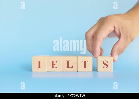 Esame o concetto di test del sistema di test in lingua inglese internazionale o IELTS. Blocchi di legno piatto tipografico giacitura su sfondo blu. Foto Stock