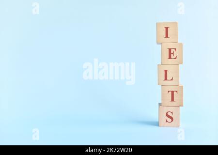 Esame o concetto di test del sistema di test in lingua inglese internazionale o IELTS. Blocchi di legno piatto tipografico giacitura su sfondo blu. Foto Stock