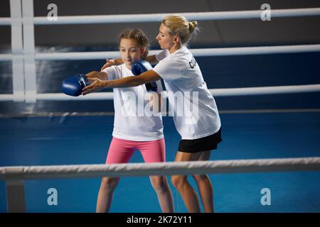 Ginnastica femminile di kickboxer con allenatore personale in palestra sportiva, al coperto. Concetto di studio, sfide, sport, hobby, competizione Foto Stock