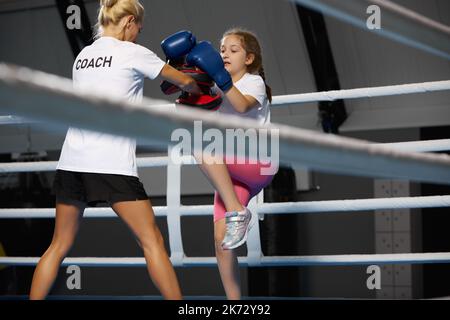 Ginnastica femminile di kickboxer con allenatore personale in palestra sportiva, al coperto. Concetto di studio, sfide, sport, hobby, competizione Foto Stock