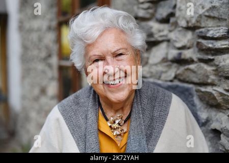 Ritratto di elegante donna anziana che si trova vicino alla vecchia casa di campagna. Foto Stock