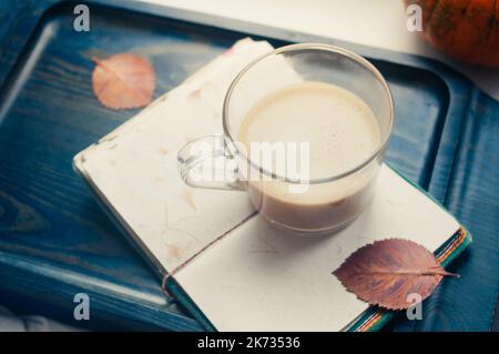 Una zucca di zucca e un caffè latte preparato con soia di avena a base di piante o latte di mandorla con taccuino vuoto al tavolo sul nero scuro b Foto Stock