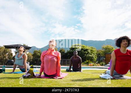 Diversi amici che praticano lo yoga e lo stretching in giardino Foto Stock