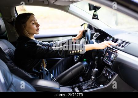 Donna mano che preme il pulsante di emergenza sulla console dell'auto, primo piano Foto Stock