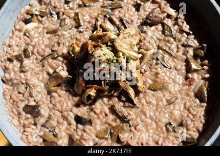 risotto rosso di funghi selvatici in una ciotola di cui bolete decorato con parasolo fritto. Foto di alta qualità Foto Stock