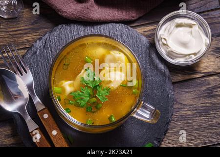 Brodo fresco con gnocchi in recipiente di vetro sul tavolo vista Foto Stock