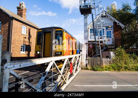 Treni delle East Midlands, classe 156, 156497, all'incrocio a livello, alla stazione, alla cassa di segnale e all'attraversamento manuale a livello. Heckington Village, Lincolnshire, Ingla Foto Stock