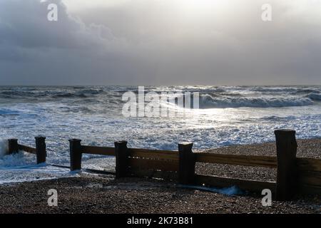 Onde che si infrangono sulla spiaggia di Bexhill-on-Sea con nuvole tempesta e una spiaggia groyne Foto Stock