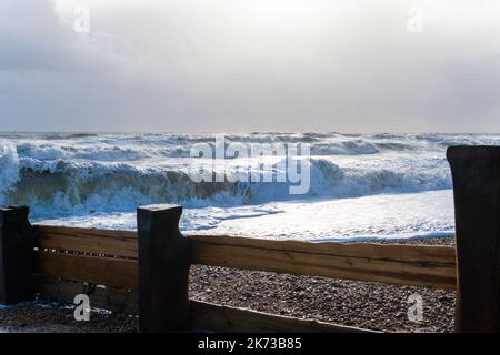 Onde che si infrangono sulla spiaggia di Bexhill-on-Sea con nuvole tempesta e una spiaggia groyne Foto Stock