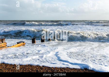 Onde che si infrangono sulla spiaggia di Bexhill-on-Sea con nuvole tempesta e una spiaggia groyne Foto Stock
