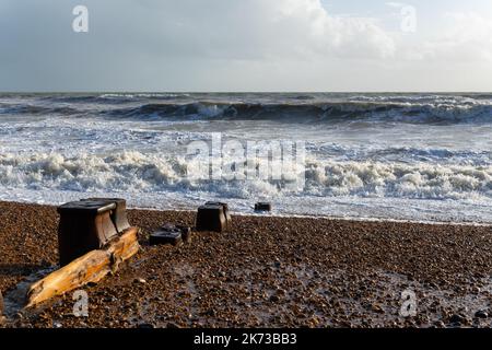Onde che si infrangono sulla spiaggia di Bexhill-on-Sea con nuvole tempesta e una spiaggia groyne Foto Stock
