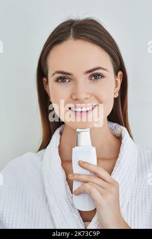 Felice donna caucasica con ecografia scrubber cura la sua pelle per rimuovere le teste nere e pulizia della pelle del viso, su sfondo bianco. Ultrasuoni viso Foto Stock