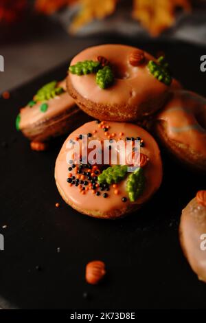 Mini ciambelle autunnali fatte in casa con glassa d'arancia, focu selettivo Foto Stock