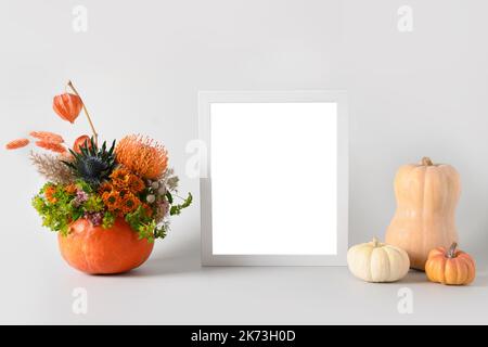 Mockup autunnale con bouquet di fiori in zucca, elementi decorativi e cornice bianca su sfondo bianco. Spazio di copia. Modello autunnale. Foto Stock