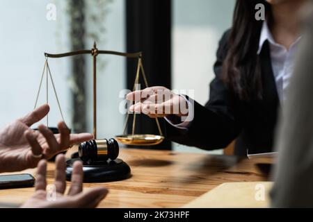 Uomini d'affari e avvocati che discutono di documenti contrattuali con scala di ottone su una scrivania di legno in ufficio. Diritto, servizi legali, consulenza, concetto di giustizia Foto Stock