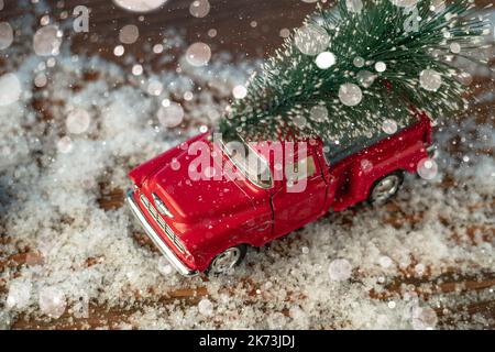 Un giocattolo rosso retrò auto porta un albero di Natale a Natale e Capodanno Foto Stock