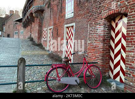 Particolare dalla porta medievale chiamata Koppelpoort in Amersfoort, Paesi Bassi. Una bici rossa è parcheggiata davanti al cancello. Foto Stock