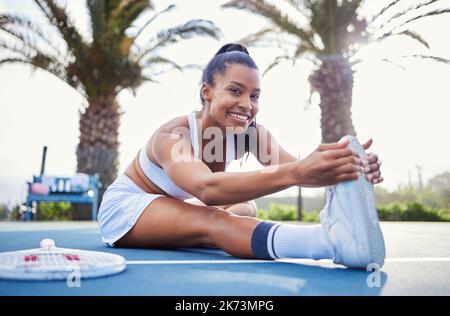 Fai quello che serve per vincere. una giovane donna attraente seduta da sola e stretching prima di giocare a tennis. Foto Stock