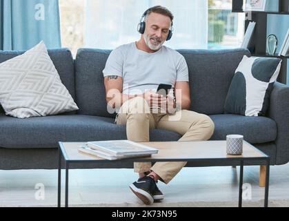 Vivere la vita dei sogni. un uomo maturo che ascolta musica utilizzando il suo smartphone a casa. Foto Stock