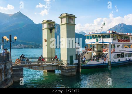 Traghetto Lago di Como moto, vista in estate dei motociclisti a bordo di un traghetto attraccato al molo nella pittoresca città di Bellagio, Italia Foto Stock