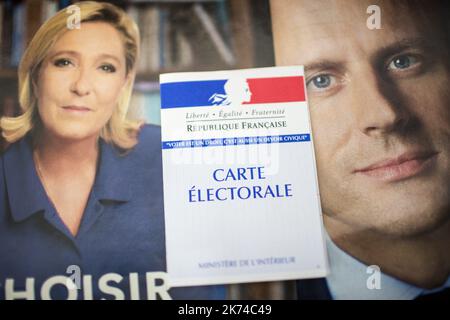 Illustrazione, una scheda di registrazione degli elettori francesi è vista davanti ai manifesti ufficiali della campagna elettorale dei candidati alle elezioni presidenziali francesi, leader del partito politico del fronte nazionale francese (FN), Marine le Pen e presidente del movimento politico 'en Marche ! (A partire da !) Emmanuel Macron il 05 maggio 2017 a Parigi, Francia. Foto Stock