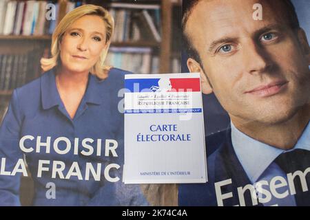 Illustrazione, una scheda di registrazione degli elettori francesi è vista davanti ai manifesti ufficiali della campagna elettorale dei candidati alle elezioni presidenziali francesi, leader del partito politico del fronte nazionale francese (FN), Marine le Pen e presidente del movimento politico 'en Marche ! (A partire da !) Emmanuel Macron il 05 maggio 2017 a Parigi, Francia. Foto Stock