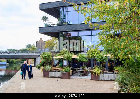 Una coppia cammina lungo l'alzaia del canale Regents a King's Cross, Londra, Regno Unito, il gastropub Lighterman sulla destra. Foto Stock