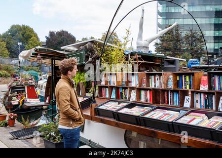 Un cliente che naviga in Word on the Water, alias The London Bookbarge, una libreria galleggiante sul Regents Canal a King's Cross, Londra, Regno Unito Foto Stock