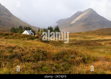 Gruppo di escursionisti che si avvicinano al rifugio Lagangarbh all'inizio del Buachaille Etive Mor camminano dal parcheggio Altnafeadh in autunno, Glen Coe, Scozia, Regno Unito Foto Stock