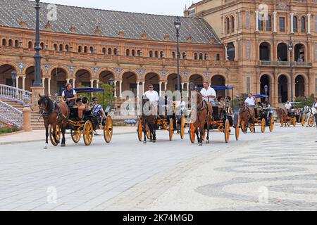 SIVIGLIA, SPAGNA - 21 MAGGIO 2017: Ci sono carrozze retrò trainate da cavalli con turisti in un tour di Piazza di Spagna. Foto Stock