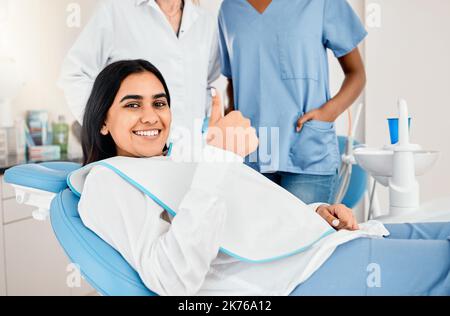 Pronto per una bocca pulita e fresca. una giovane donna nel suo ufficio dentista che dà i pollici in su. Foto Stock