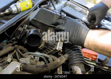 La mano del meccanico è filtro dell'aria dell'automobile di ricambio nel motore dell'automobile nel centro di assistenza Foto Stock