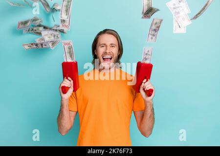 Foto di un ragazzo ben impressionato vestito t-shirt arancione sparare vincendo cash isolato colore sfondo teal Foto Stock