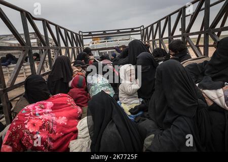 Il PG curdo della coalizione (forze democratiche siriane AKA SDF) sta portando migliaia di donne e bambini dei jihadisti di Daesh (ISIS) fuori da Baghouz, l'ultima roccaforte jihadista in Siria, in camion per farli cadere nel campo di al Hol a poche ore di distanza. Foto Stock