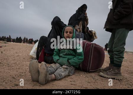 Il PG curdo della coalizione (forze democratiche siriane AKA SDF) sta portando migliaia di donne e bambini dei jihadisti di Daesh (ISIS) fuori da Baghouz, l'ultima roccaforte jihadista in Siria, in camion per farli cadere nel campo di al Hol a poche ore di distanza. Foto Stock